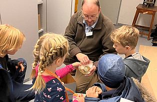 Der Archivleiter zeigt den Kindern ein Modell aus Holz.