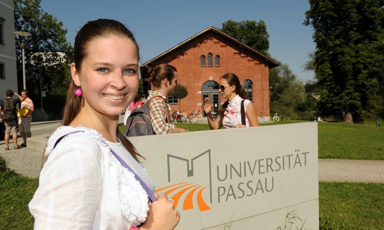 Female student in front of the stele with the university logo