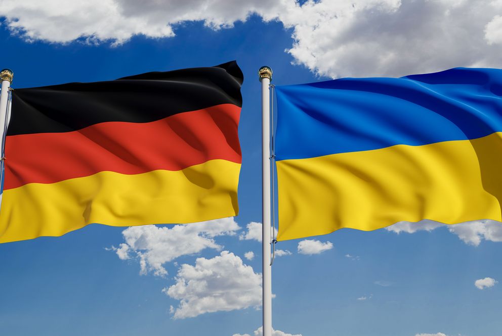 Die deutsche und die ukrainische Flagge vor blauem Himmel.