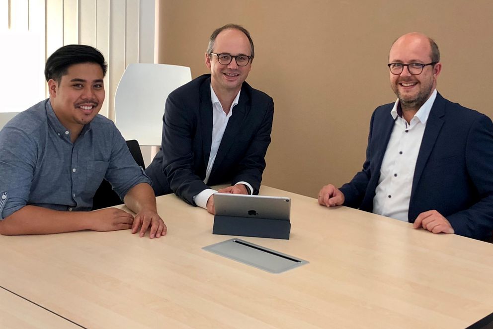 Drei Personen, die an einem Tisch sitzen, beim Besuch der Werner Kopfermann GmbH
