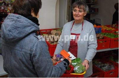 Lebensnotwendige Hilfe: Die Vorsitzende des Vereins „Passauer Tafel e.V.“, Reinhilde Keilbach (r.), übergibt einen Korb mit Gemüse, Obst, Milch und Schokolade an eine Frau. Nach Weihnachten hat die Tafel viele Süßigkeiten zu verteilen, weil die Ge