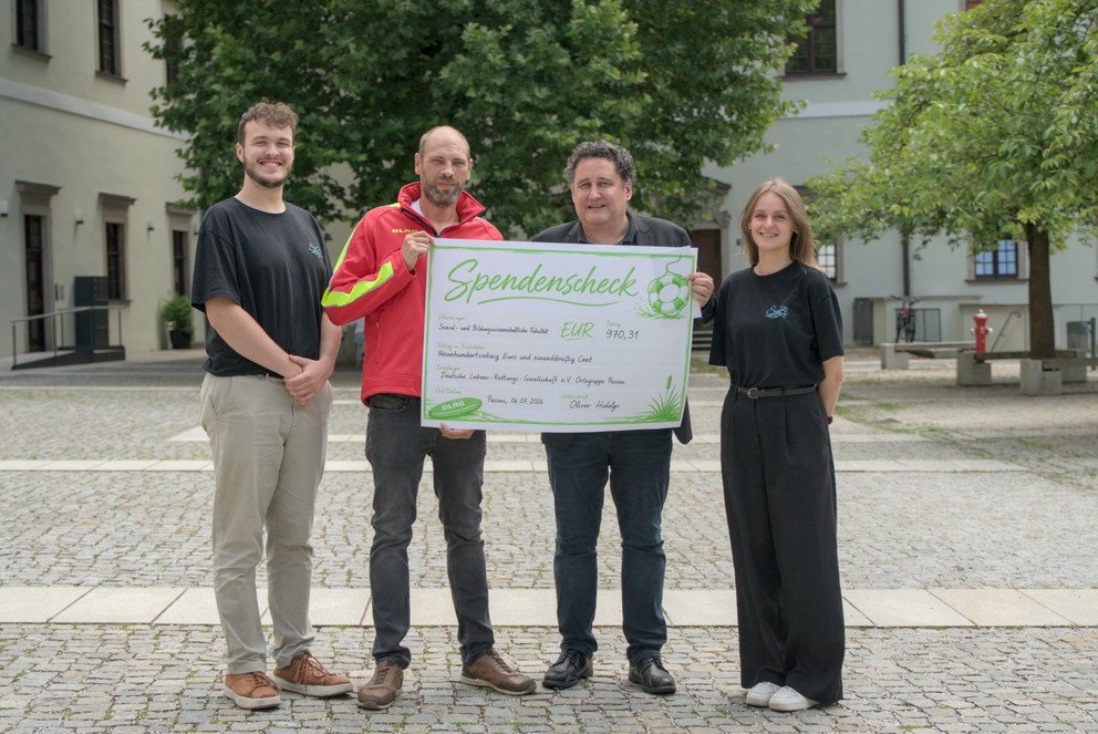 &Uuml;bergabe des Spendenschecks (v.l.n.r.): Marvin Kraus (Fachschaft SoBi) Thomas Schneider (DLRG Passau), Dekan Prof. Dr. Oliver Hidalgo, Katharina Obermaier (Fachschaft SoBi) ; Foto: Malte Sigmund.