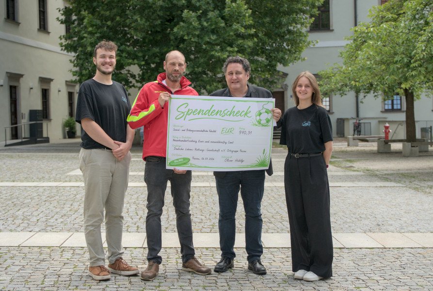 Übergabe des Spendenschecks (v.l.n.r.): Marvin Kraus (Fachschaft SoBi) Thomas Schneider (DLRG Passau), Dekan Prof. Dr. Oliver Hidalgo, Katharina Obermaier (Fachschaft SoBi) ; Foto: Malte Sigmund.