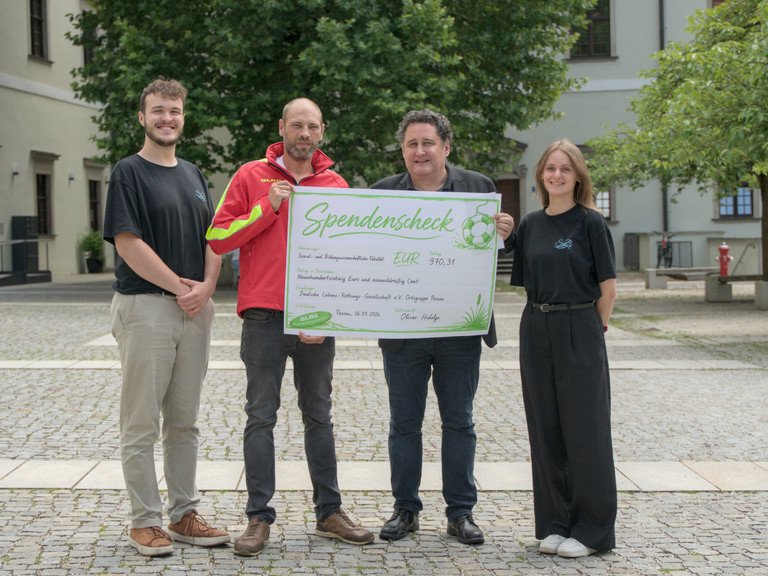 &Uuml;bergabe des Spendenschecks (v.l.n.r.): Marvin Kraus (Fachschaft SoBi) Thomas Schneider (DLRG Passau), Dekan Prof. Dr. Oliver Hidalgo, Katharina Obermaier (Fachschaft SoBi) ; Foto: Malte Sigmund.