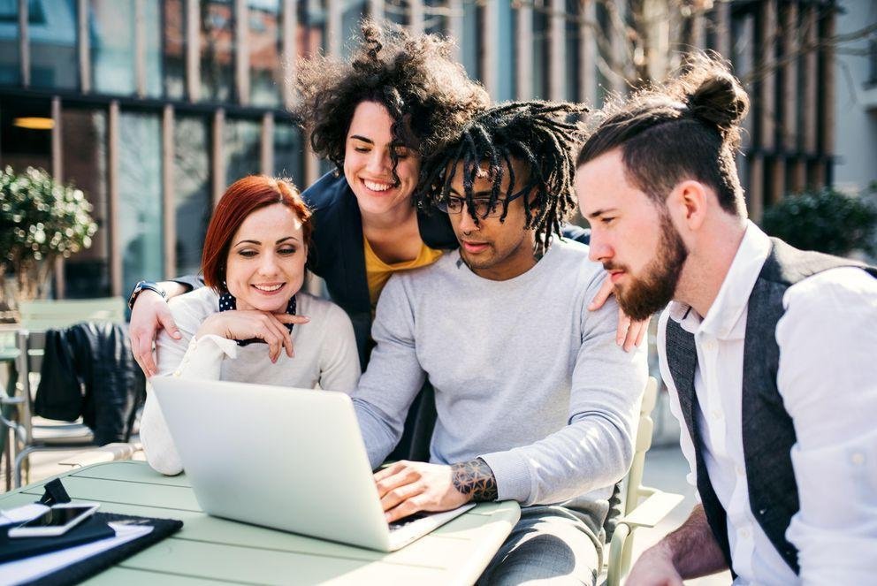 Gruppe von vier jungen Geschäftsleute sitzt zusammen um einen Laptopsammen