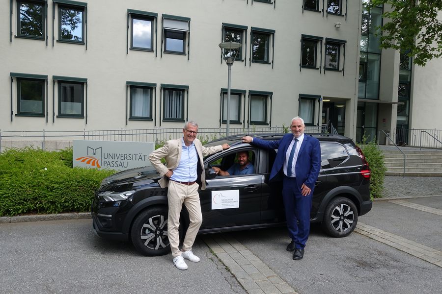 Präsident Prof. Dr. Ulrich Bartosch (r.), Dr. Fritz Audebert (l.) und Hausmeister Bruno Vegh (im Wagen) nehmen das neue Auto in Empfang. Foto: Universität Passau