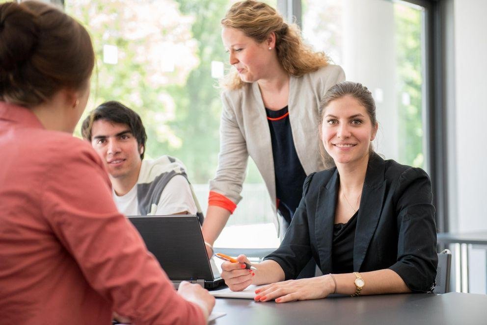 [Translate to Englisch:] Drei Frauen und ein Mann sitzen zusammen und arbeiten gemeinsam an einem Projekt.