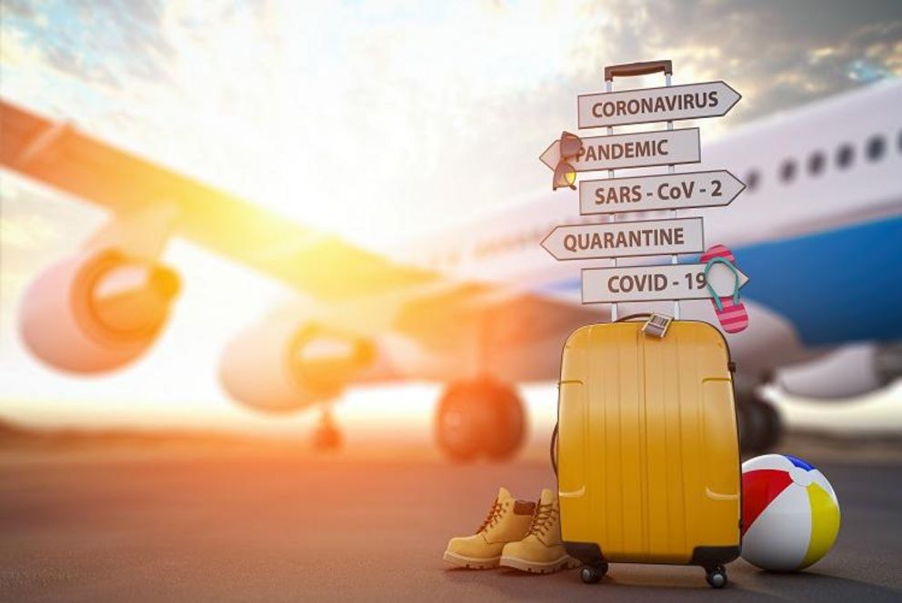 Ein gelber Koffer, Wanderschuhe und ein Wasserball stehen vor einem abflugbereiten Flugzeug auf der Rollbahn. 