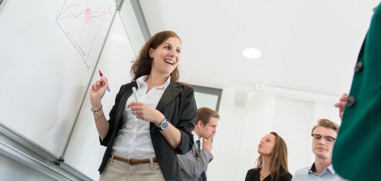 Dozentin schreibt etwas an ein Whiteboard