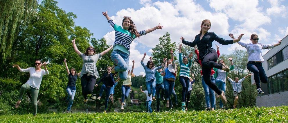 Studierende springen auf einer Wiese