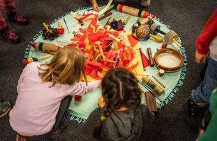 Kinder im Workshop "Feurige Musik" sitzen im Kreis um Instrumente