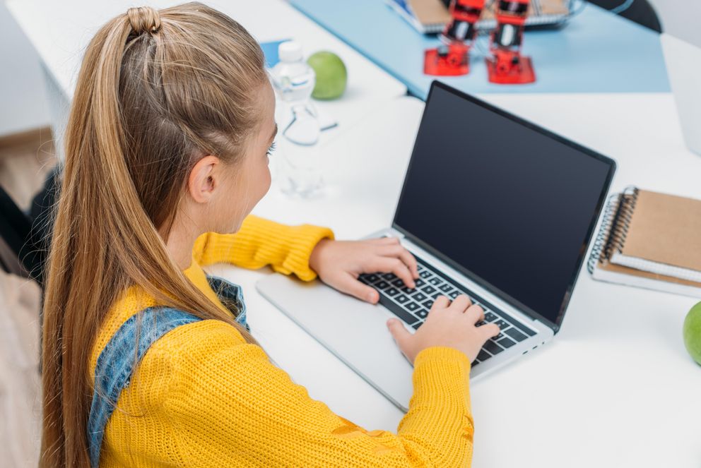 Mädchen sitzt am Laptop und nimmt am Programmierkurs teil