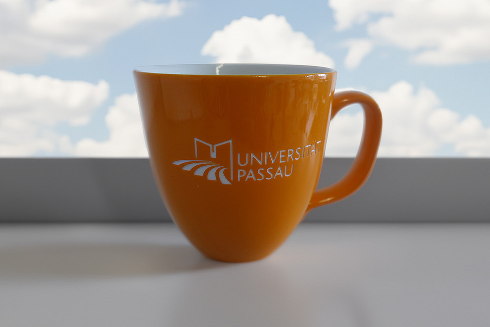 Tasse in orange mit Uni-Logo, graviert