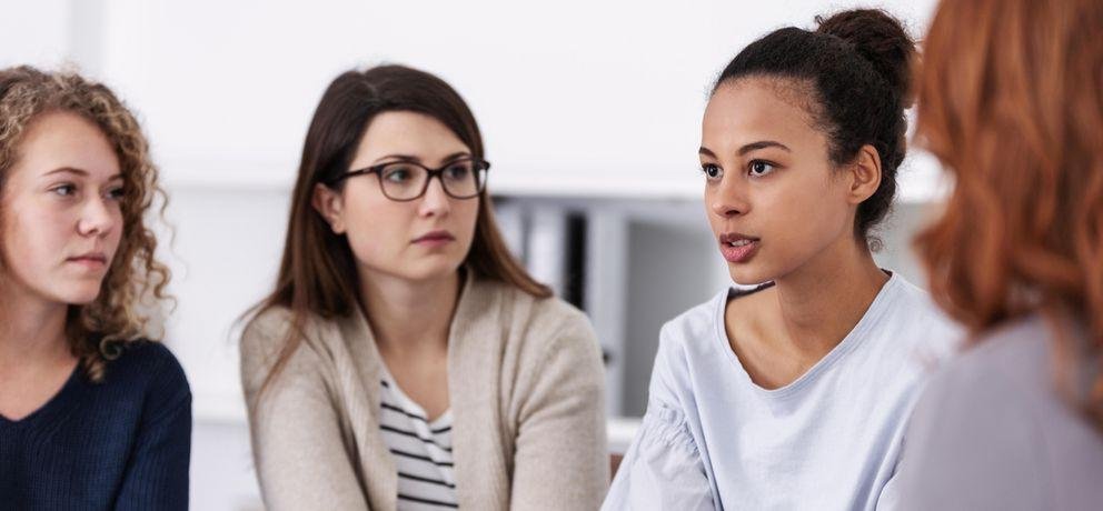 Frauen sitzen nebeneinander und sind im Gespräch