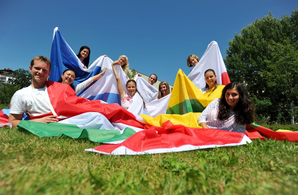 Studierende mit der Flagge Ihres Landes auf einer Wiese