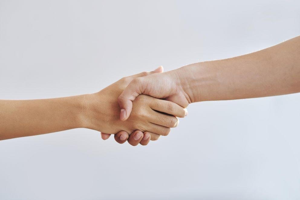 Two shaking hands in front of a white background