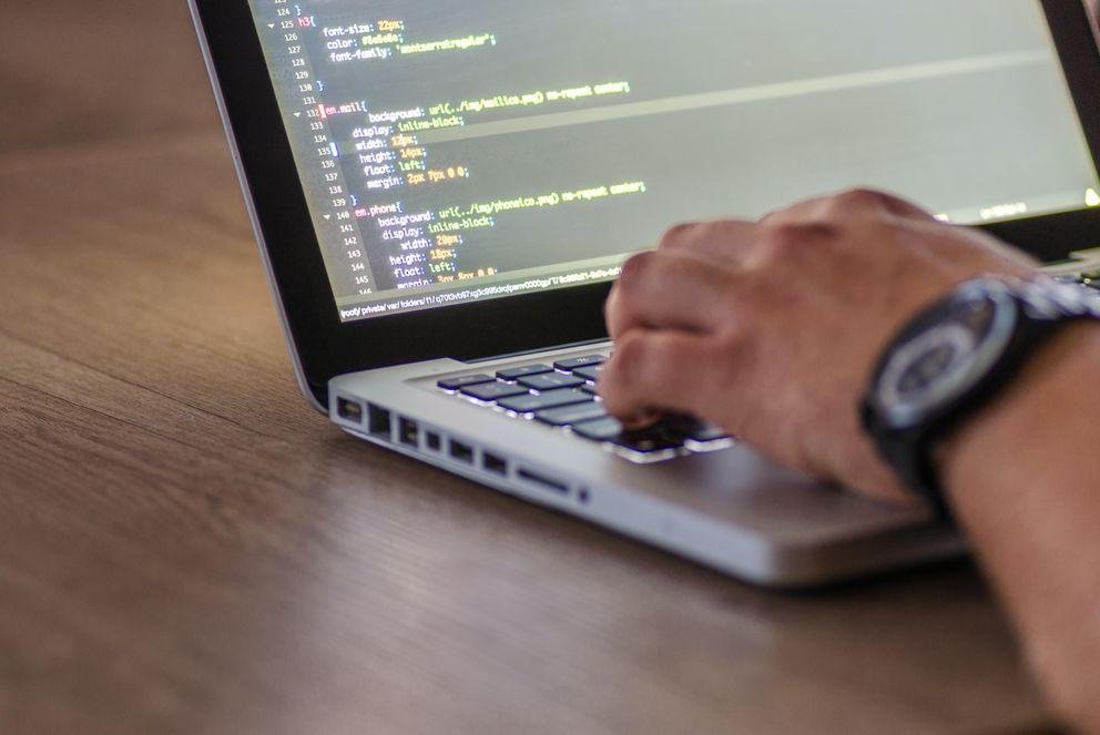 Person schreibt Code auf Laptop
