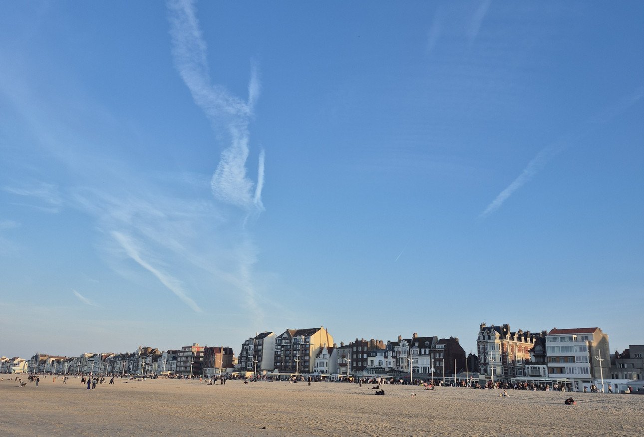 Blick auf die Strandpromenade von Dunkerque mit historischen H&auml;usern bei klarem Himmel.