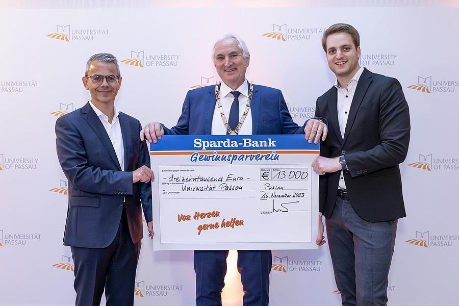 Michael Gruber, Vorstandsvorsitzender der Sparda-Bank Ostbayern eG (li), übergab gemeinsam mit Stephan Brandler, Leiter der Sparda-Bank-Filiale Passau (re) den Spendenscheck an Universitätspräsident Prof. Dr. Ulrich Bartosch (Mitte); Foto: Universität Passau