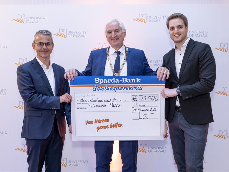 Michael Gruber, Vorstandsvorsitzender der Sparda-Bank Ostbayern eG (li), übergab gemeinsam mit Stephan Brandler, Leiter der Sparda-Bank-Filiale Passau (re) den Spendenscheck an Universitätspräsident Prof. Dr. Ulrich Bartosch (Mitte); Foto: Universität Passau