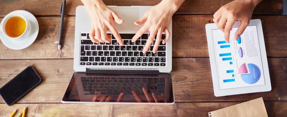Handy, Laptop mit Händen und Tee auf Holztisch