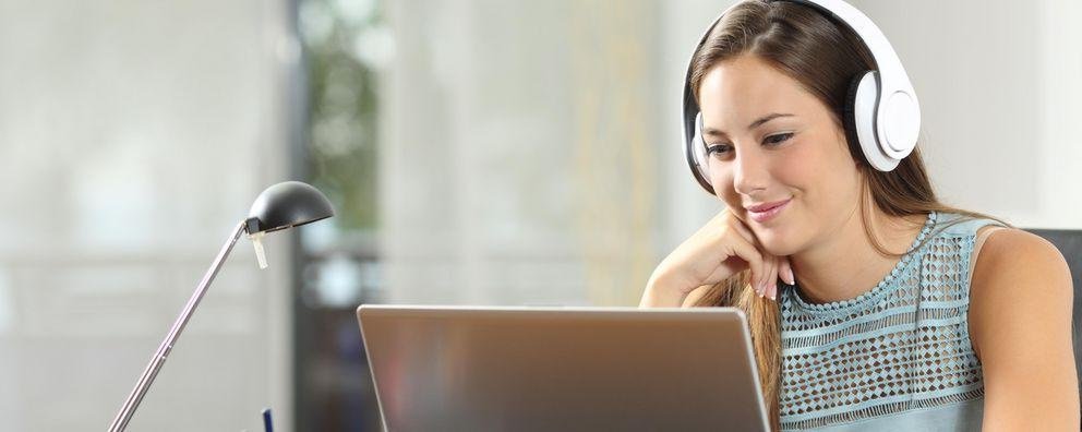 Eine Frau sitzt vor ihrem Laptop und nimmt an einem Webinar teil
