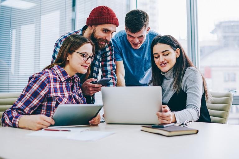 Gruppe Studierender schaut auf einen Laptop 