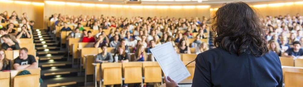 Symbolbild: Professorin redet im Hörsaal zu Student:innen