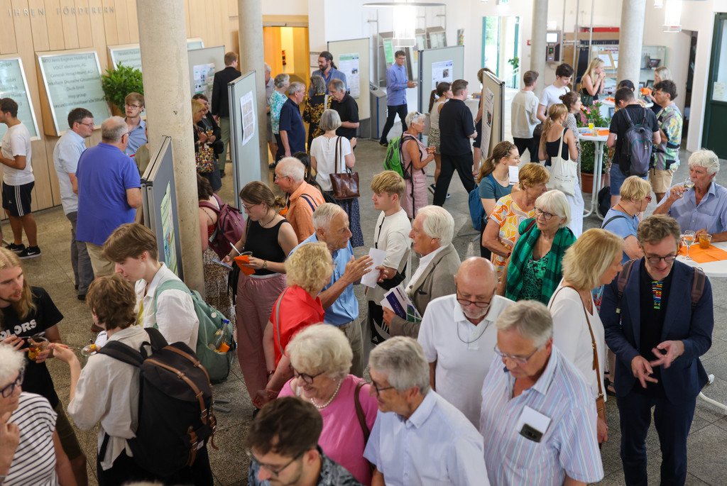 Blick in das Foyer des Audimaxes der Universität Passau auf eine große Menge an Menschen, die am Stehempfang teilnimmt.