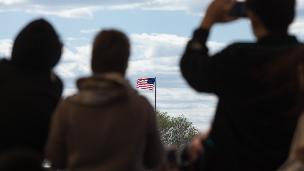 Silhouetten von Reisenden, die auf die Flagge der Vereinigten Staaten von Amerika blicken.