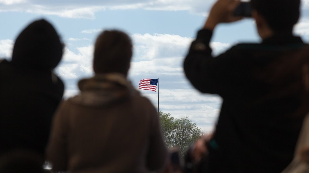 Silhouetten von Reisenden, die auf die Flagge der Vereinigten Staaten von Amerika blicken.