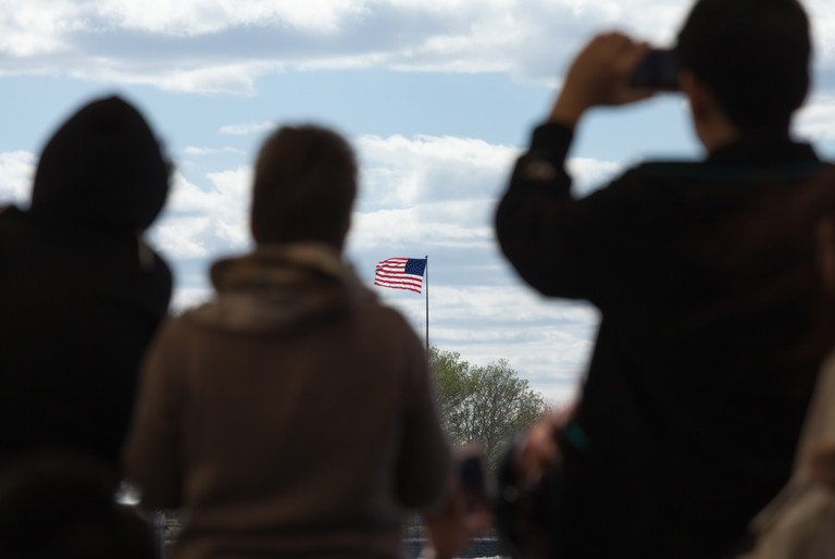 Silhouetten von Reisenden, die auf die Flagge der Vereinigten Staaten von Amerika blicken.