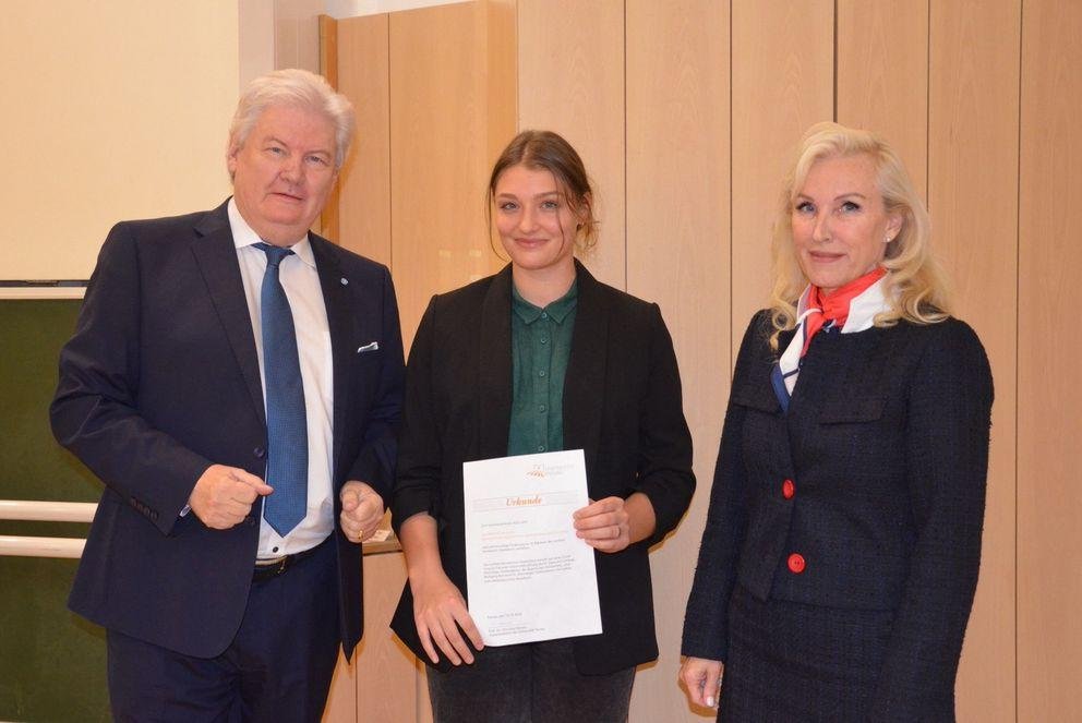 Prof. Sigmund Gottlieb (li), ehemaliger Chefredakteur des Bayerischen Fernsehens, und Prof. Dr. Christina Hansen (re), Vizepräsidentin für Internationales und Diversity, überreichten die Urkunde an Kateryna Myslytska; Foto: Nicola Jacobi