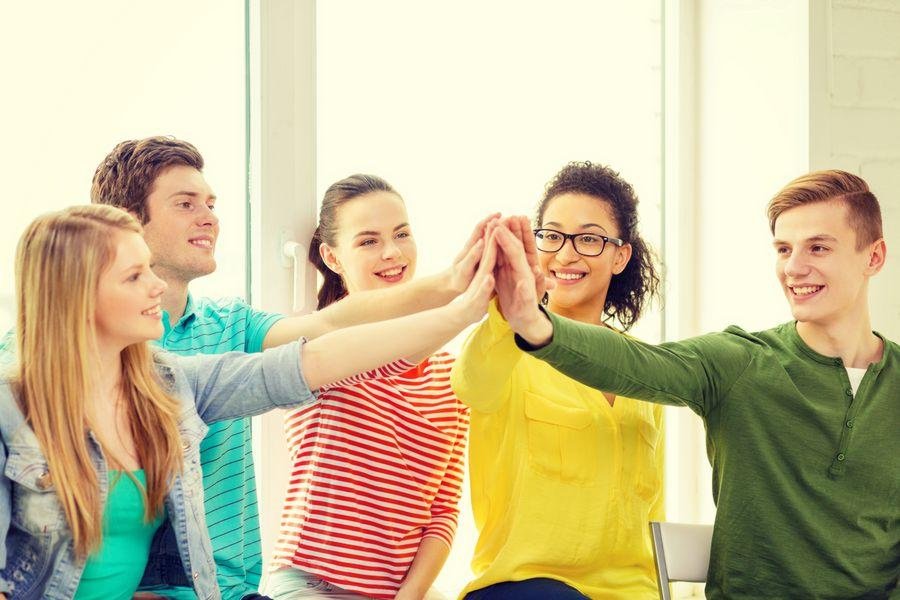 smiling students making high five gesture sitting Studierende
