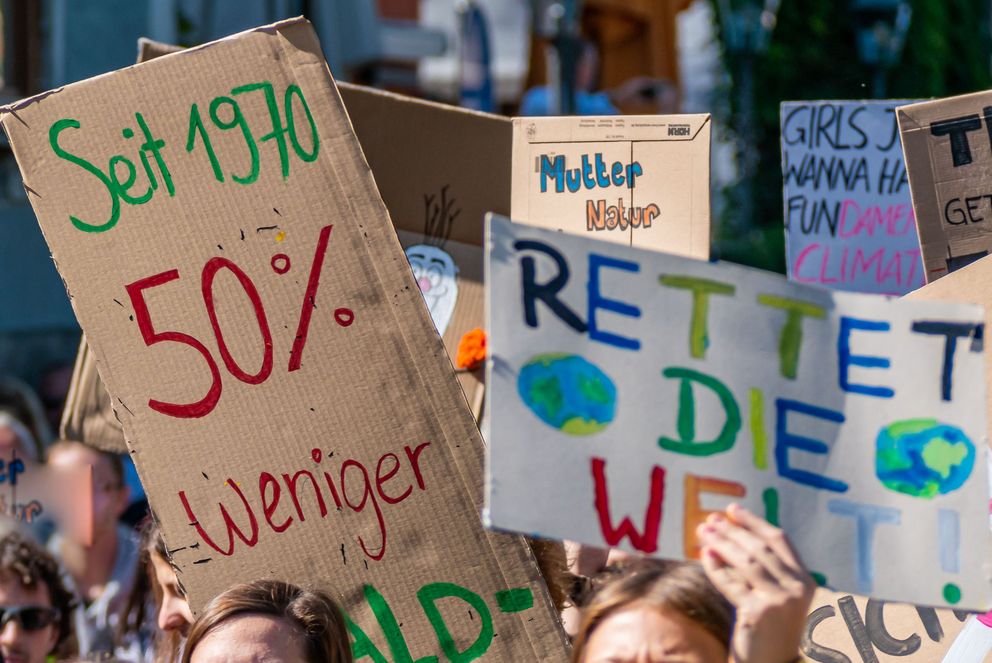 Demonstrierende auf einer Fridays-for-Future-Demonstration halten bunte Schilder für den Klimawandel hoch.