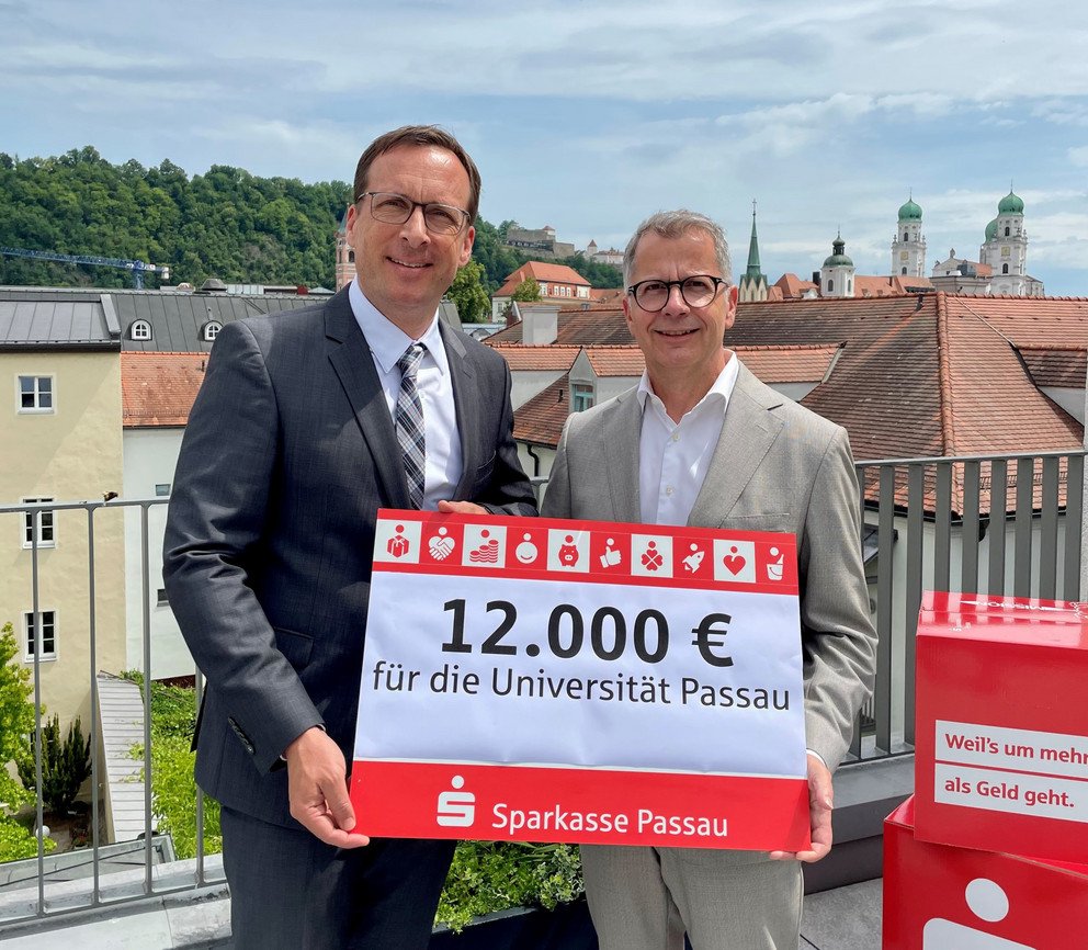 Prof. Dr. Jan Hendrik Schumann, Pr&auml;sident der Universit&auml;t Passau (l.), gemeinsam mit Christoph Helmschrott, Vorstandsvorsitzender der Sparkasse Passau, bei der Spenden&uuml;bergabe; Foto: Universit&auml;t Passau