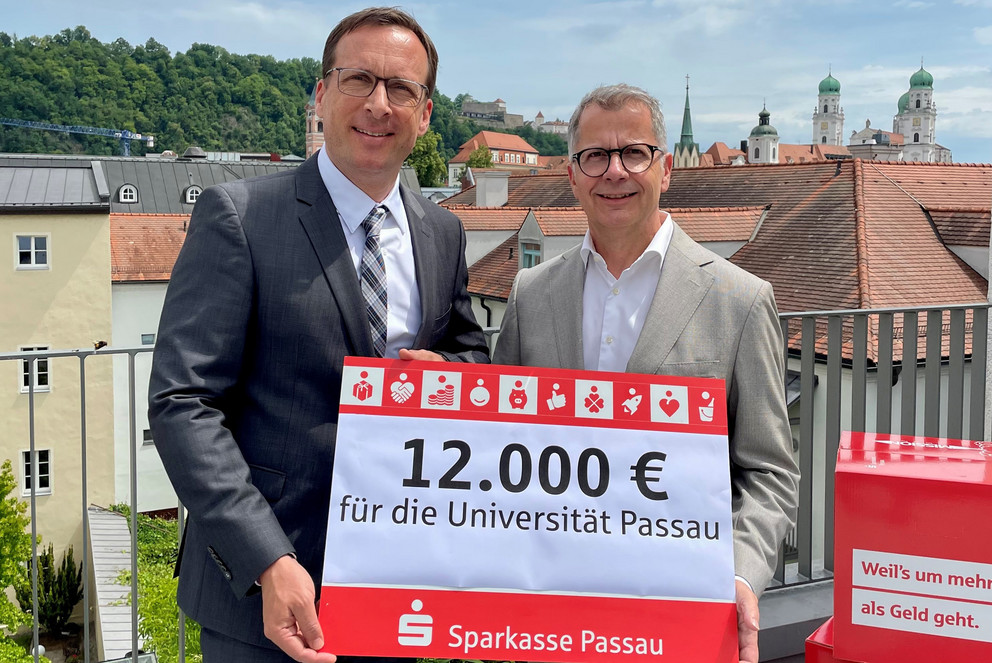 Prof. Dr. Jan Hendrik Schumann, Pr&auml;sident der Universit&auml;t Passau (l.), gemeinsam mit Christoph Helmschrott, Vorstandsvorsitzender der Sparkasse Passau, bei der Spenden&uuml;bergabe; Foto: Universit&auml;t Passau