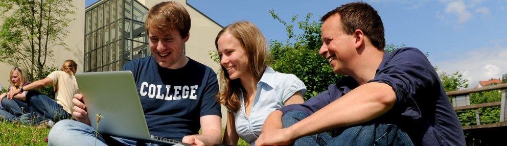 Students on the meadow with a notebook computer