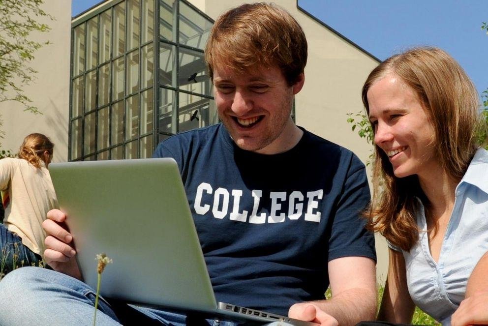 Students on the meadow with a notebook computer Students on the meadow with a notebook computer