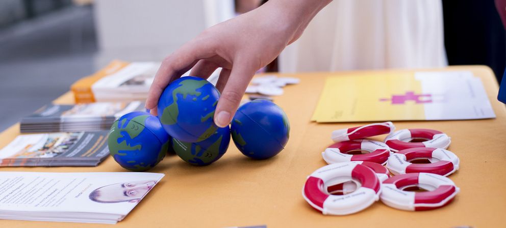 Photo: hand reaching for globe-shaped stress balls