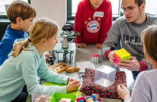 Kindern im Workshop "Mathematik zum Anfassen" wird ein Zauberwürfel erklärt