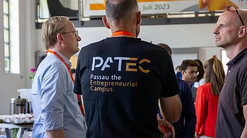 Rückansicht von Dr. Hribek mit einem schwarzen T-Shirt, auf dem präsent das PATEC-Logo abgedruckt ist.