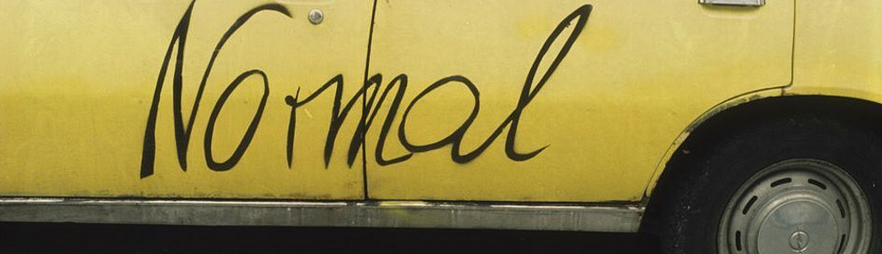 Yellow car with graffiti slogan "normal"
