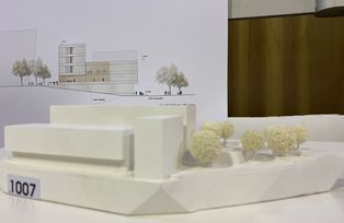 Das Modell zu Entwurf 1007 von der Seite, im Hintergrund die gezeichnete Gebäudeansicht