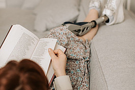 Eine Person liest ein Buch auf einem Sofa