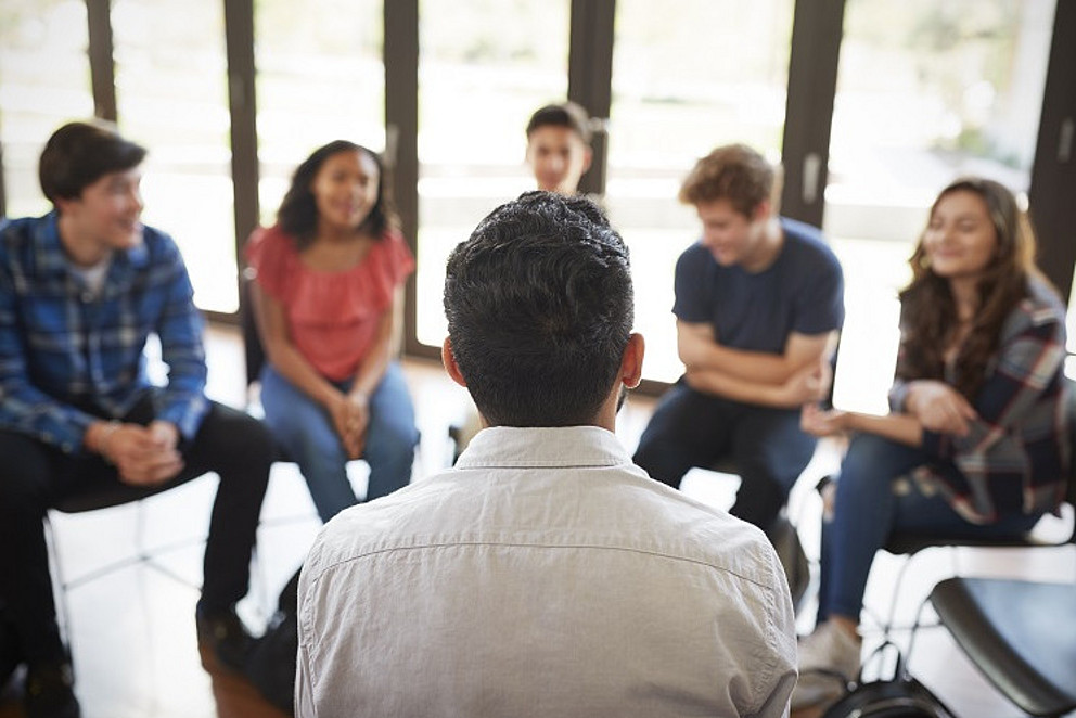 Junge Menschen sitzen in einem Kreis und diskutieren.