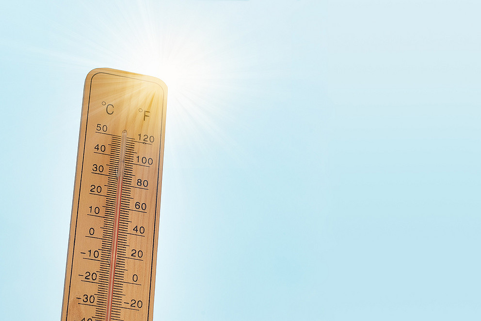 Symbolbild für Hitzewellen: ein Thermometer, das 30°C anzeigt, vor blaue Himmel und Sonnenschein