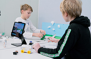  Kinder drehen einen Stop-Motion-Film mit Hilfe eines Tablets.