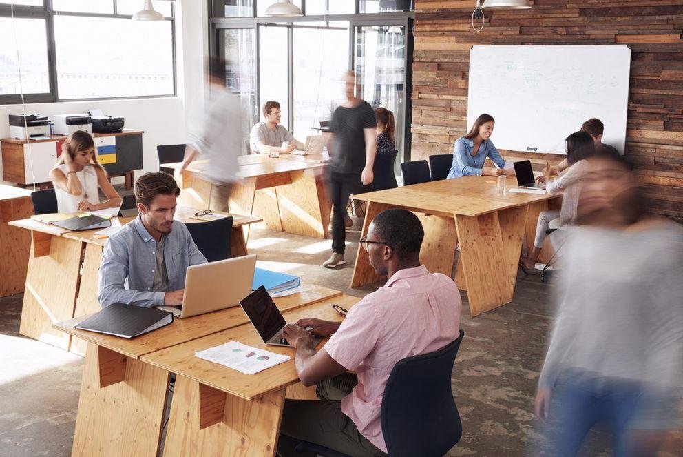 Open plan office with several people working sitting at a laptop