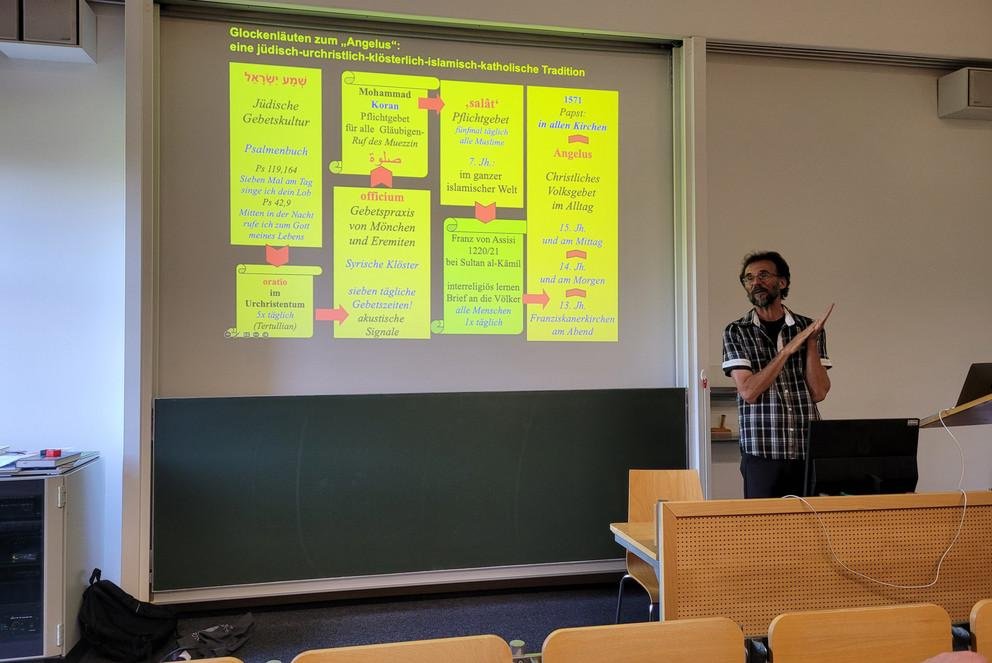 Niklaus Kuster erklärt die Herkunft des christlichen Angelus-Läutens über den Ruf des Muezzin im Islam und dessen Wurzeln wiederum im Frühchristentum und in der jüdischen Gebetkultur, Foto: Universität Passau 